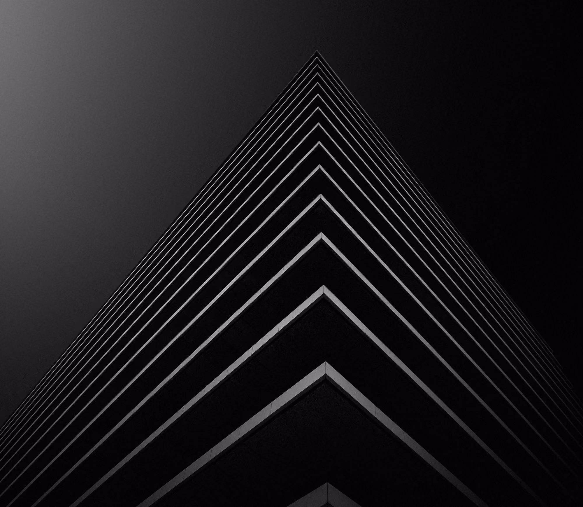 Low-angle black and white photo of modern building corner with horizontal lines in strong contrast.