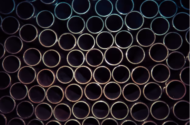 Stack of multiple metal pipes arranged horizontally with circular openings facing forward.