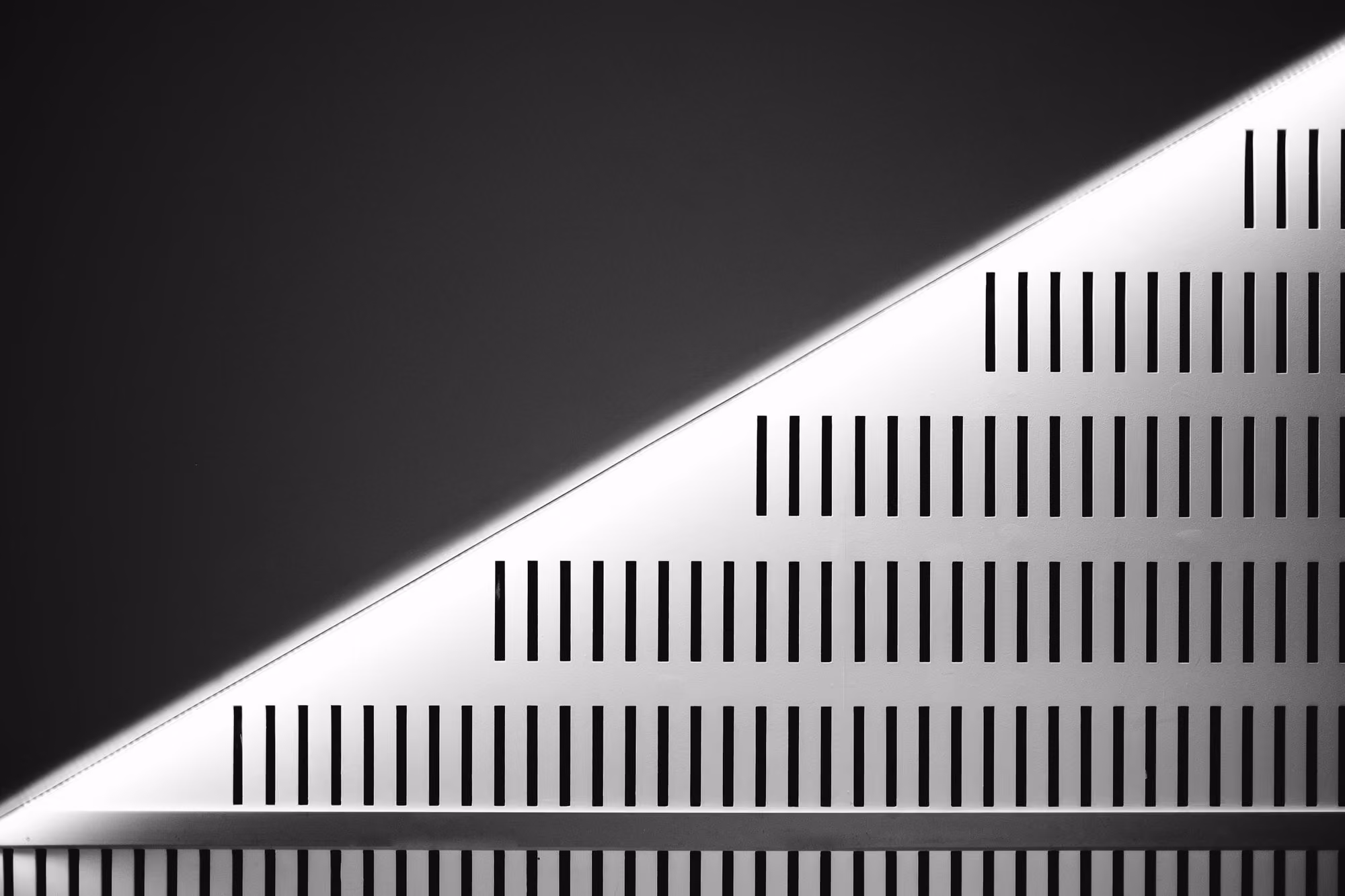 Abstract black and white photo showing diagonal light and shadow with striped pattern on a wall.
