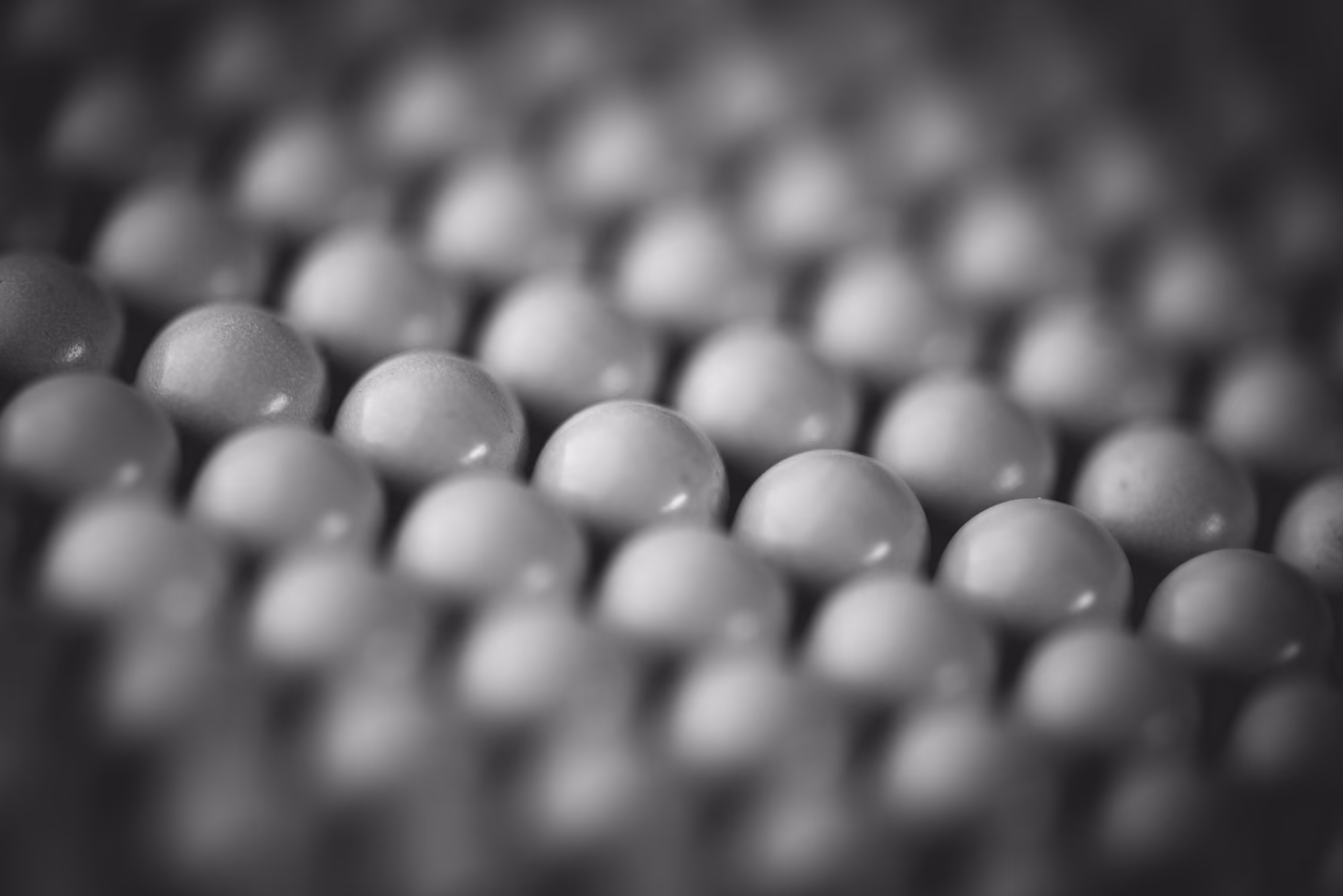 Close-up of rows of smooth, spherical balls with shallow depth of field in black and white.