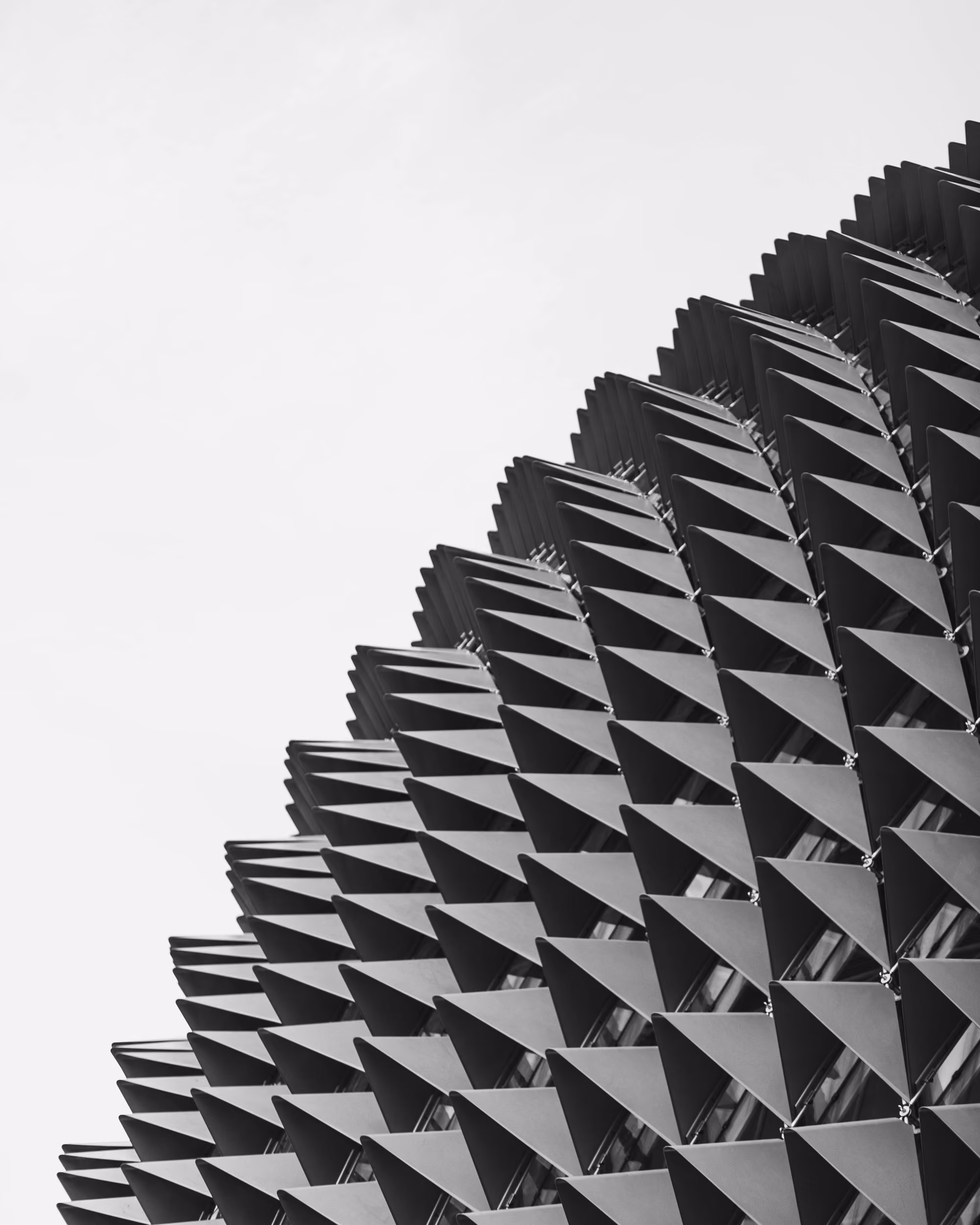Monochrome close-up of a building facade with repeating triangular architectural shades.