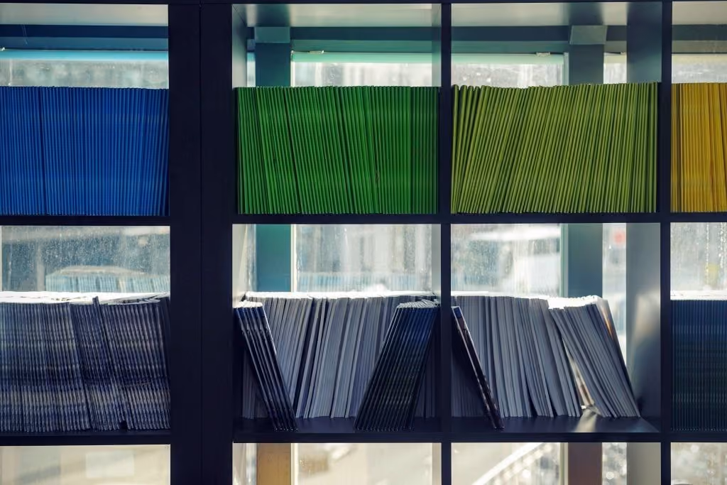 Shelves filled with organized stacks of colorful documents and magazines in front of a window.