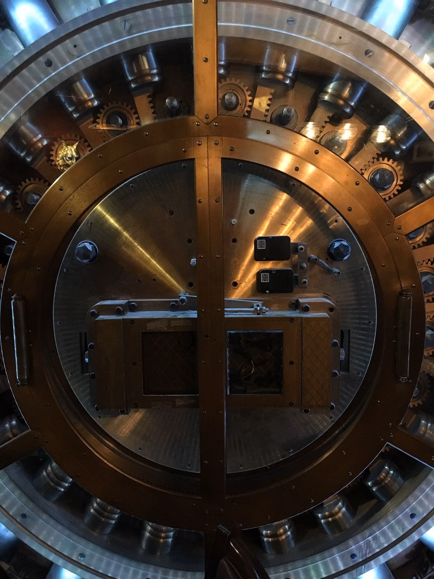 Close-up of a large, circular, metallic bank vault door with gears and locking mechanisms.