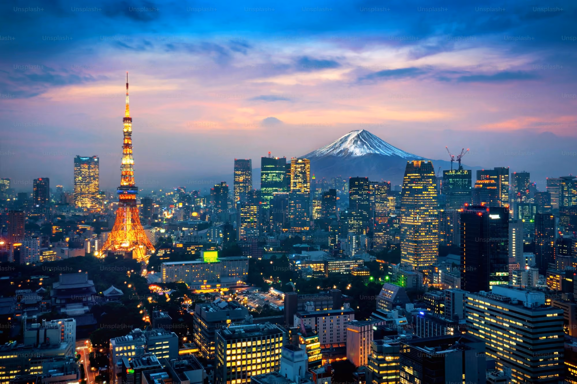 Tokyo city skyline at dusk with Tokyo Tower illuminated and Mount Fuji in the background.
