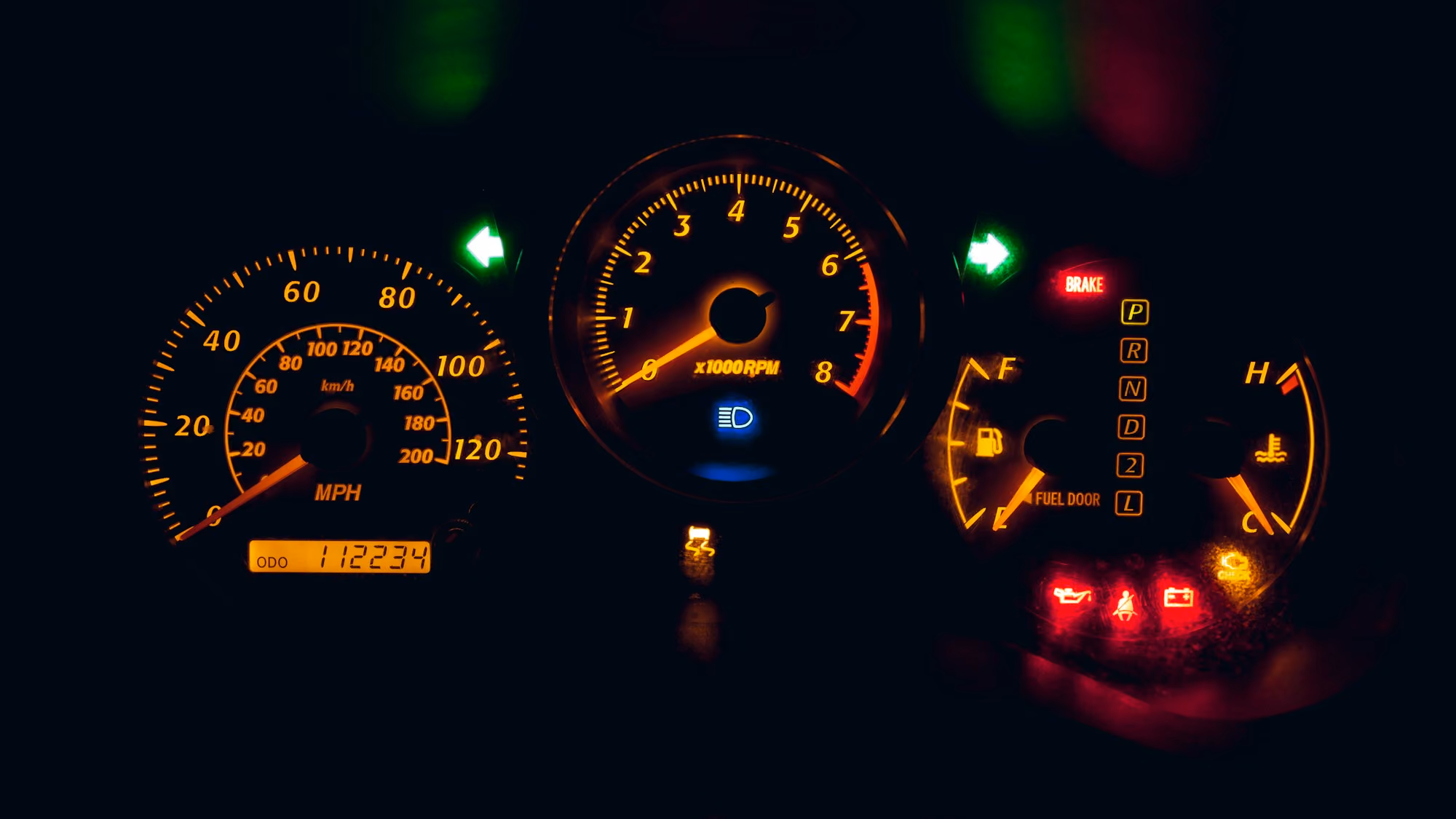 Car dashboard with speedometer, tachometer, fuel, temperature gauges, and multiple warning lights on.