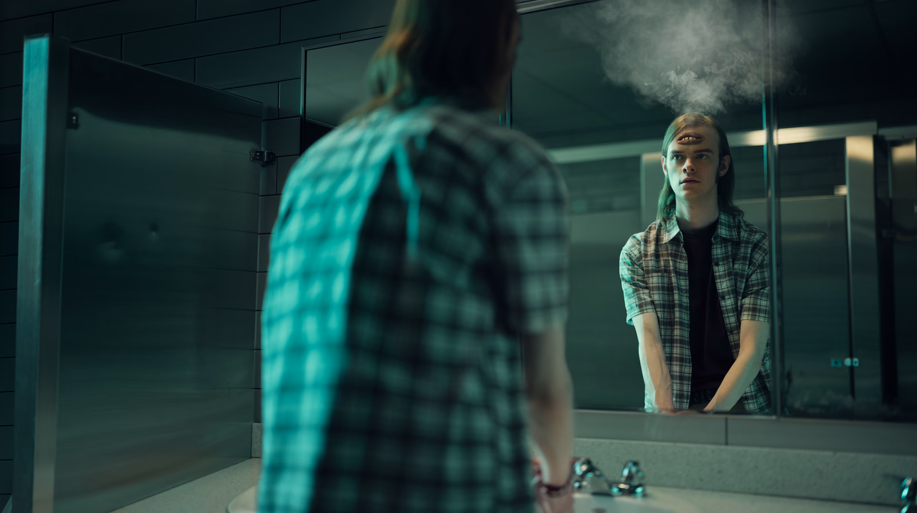 Person looks into a bathroom mirror showing a mouth on their forehead with smoke above it.