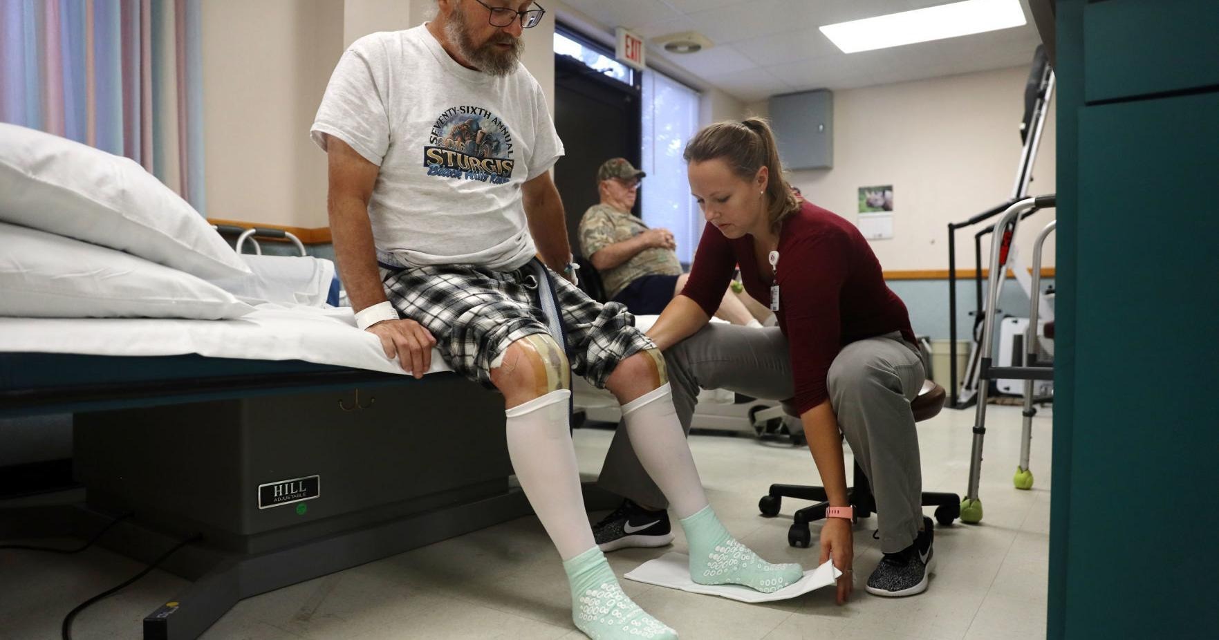 rehabilitation nurse aiding patient off hospital bed