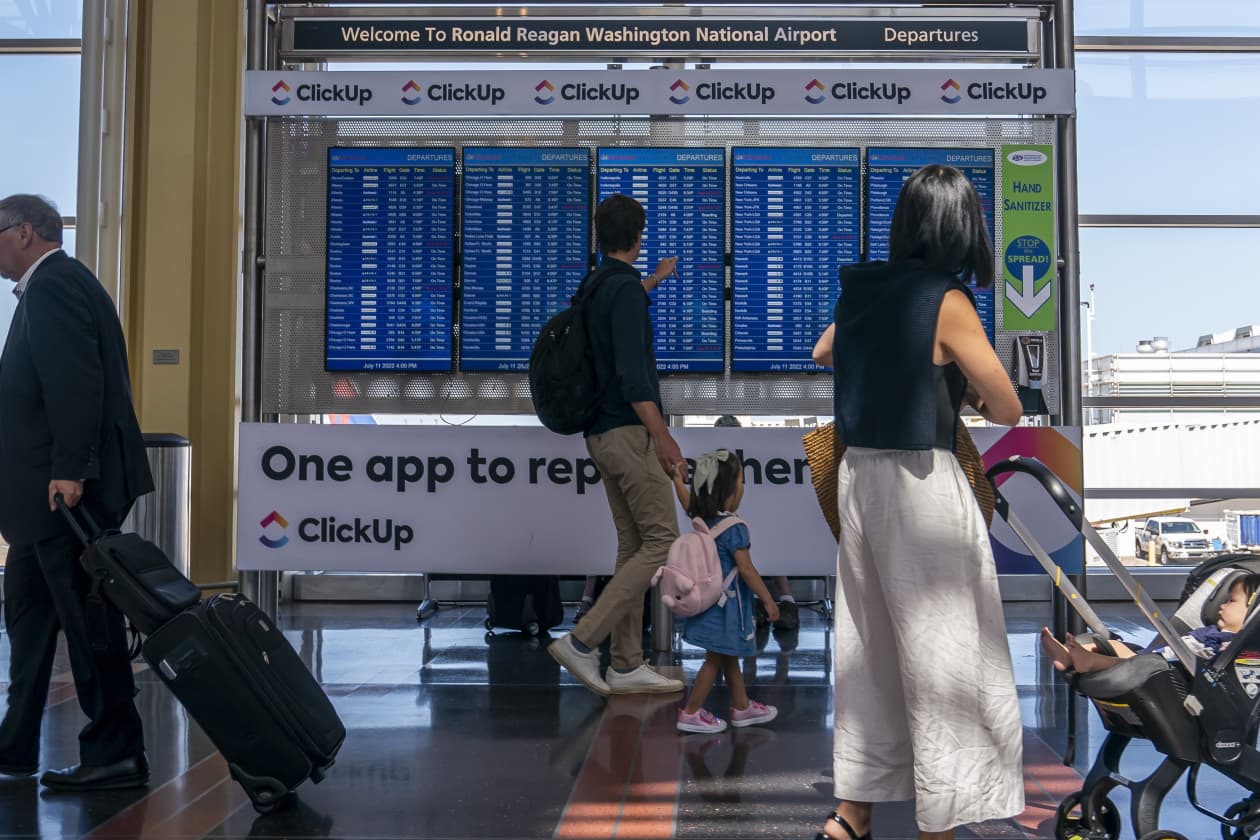 airport flight information board with passengers walking by