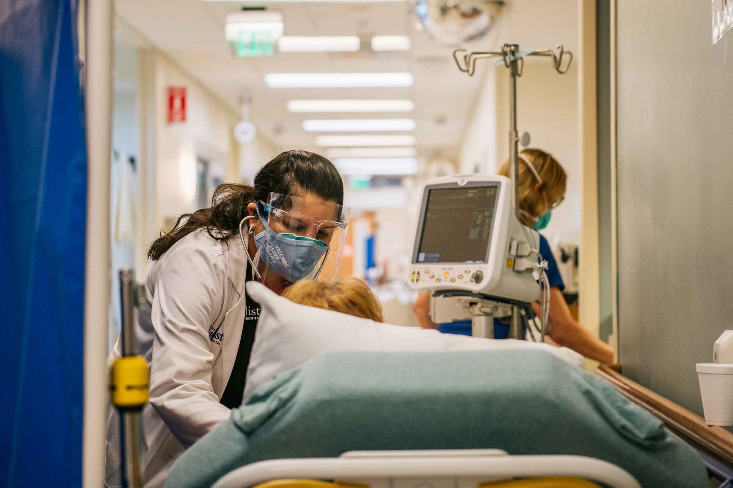 female doctor aiding patient in hospital bed