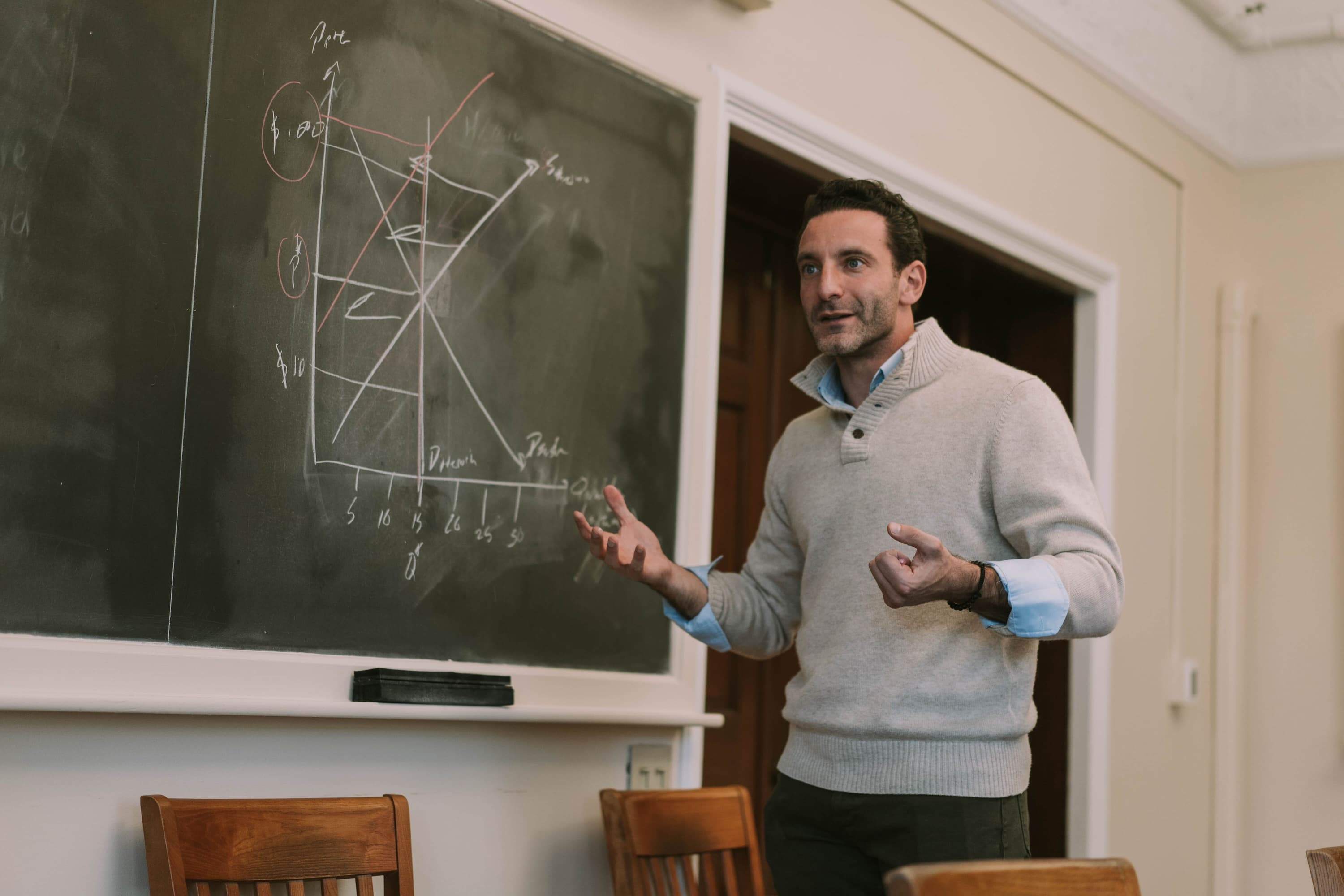 Image of Professor Zack Cooper teaching at a blackboard with a chart drawn on it 