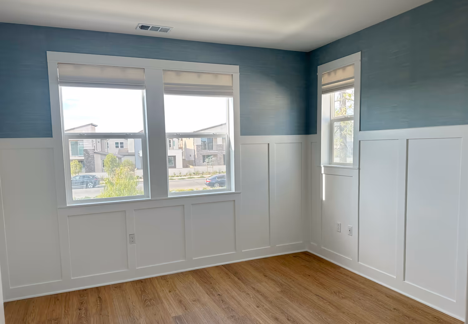 Custom wainscoting with grasscloth-style blue wallpaper in an Irvine bedroom. Clean lines and premium trim detail.