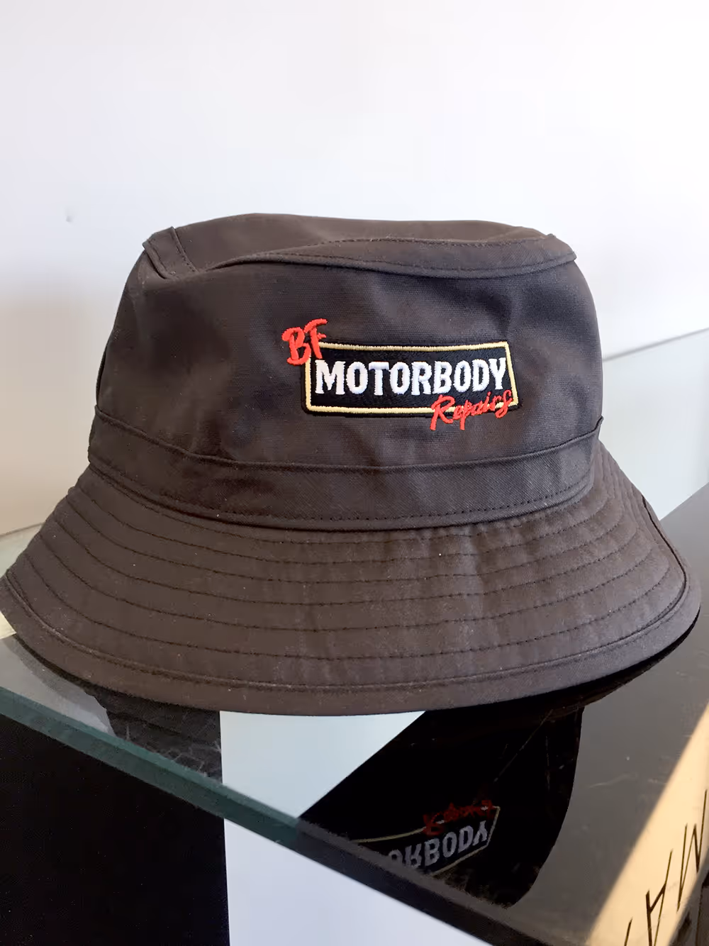 A bucket hat with the BF Motorbody Repairs logo embroidered onto the front of it