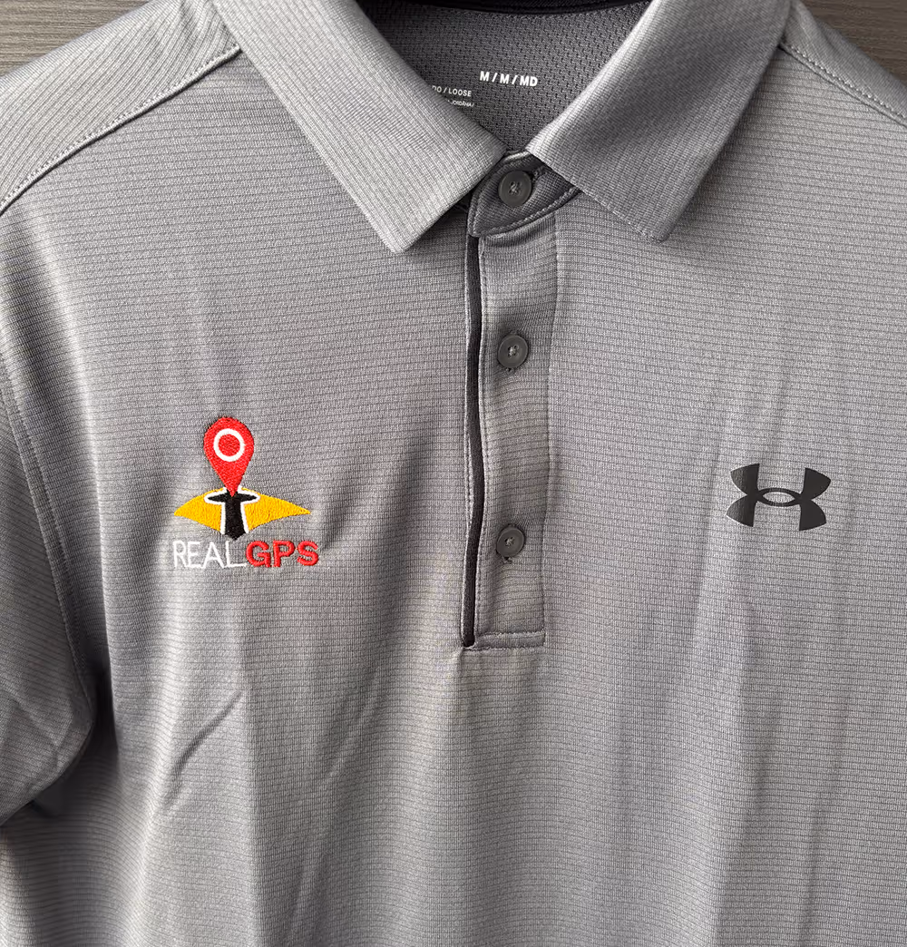 An embroidered Under Armour polo shirt with the RealGPS logo embroidered onto the front