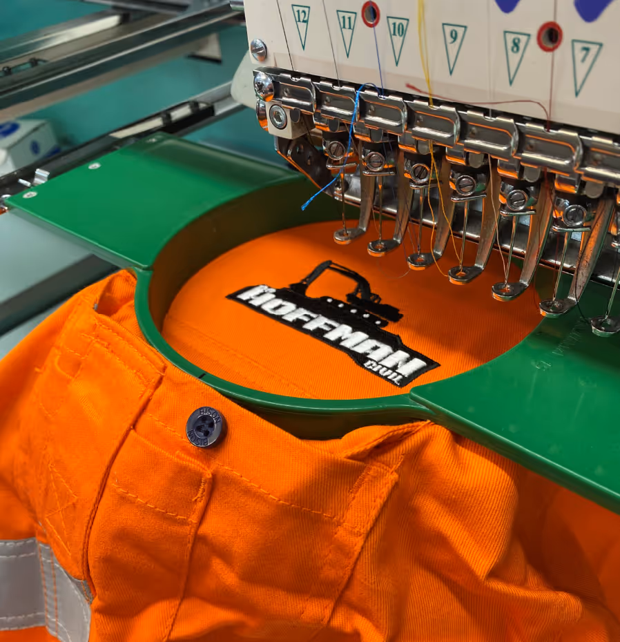 An embroidery machine in action as it embroiders a logo onto a hi-vis work shirt.