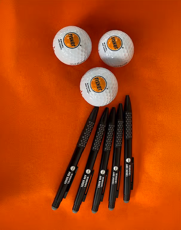 Branded golf balls and pens on an orange background