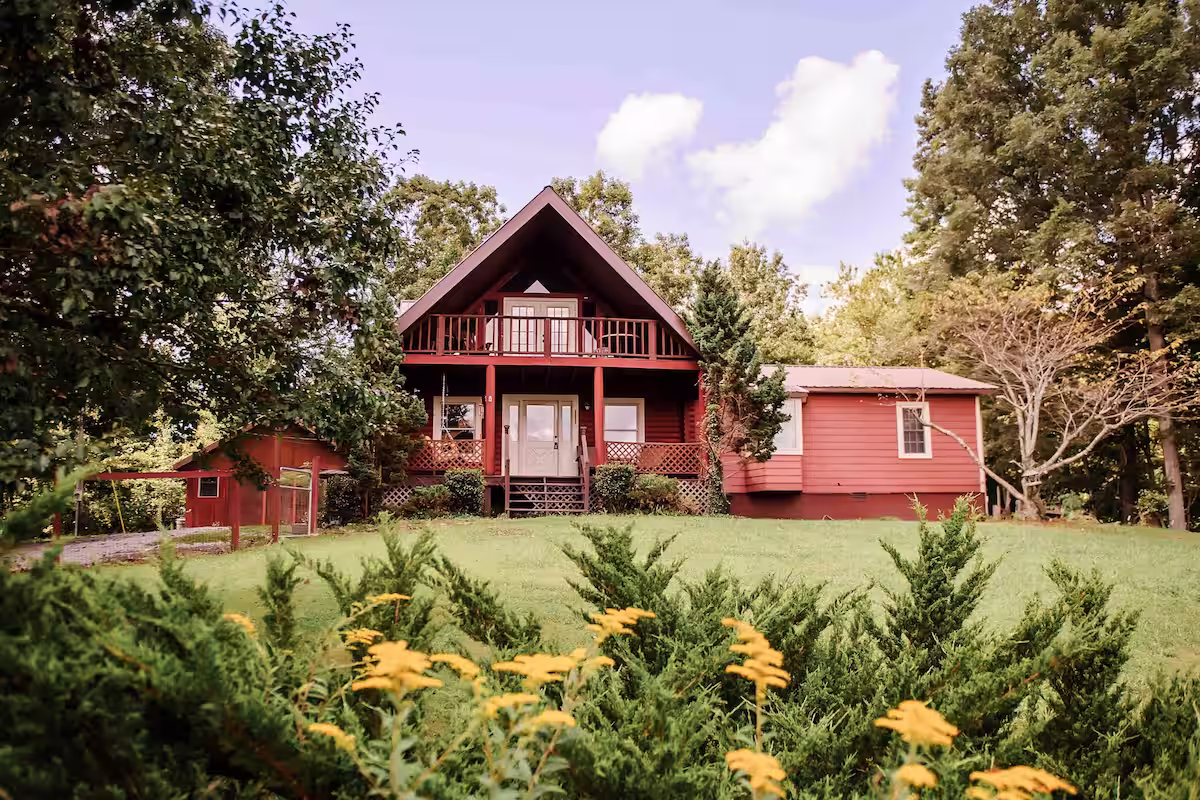 View of red home from bushes with yellow flowers