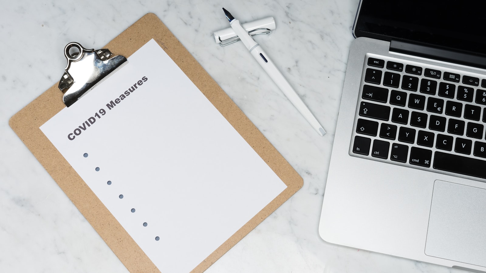 A printed checklist on a clipboard beside a laptop, illustrating documented systems that let a short-term rental run without you