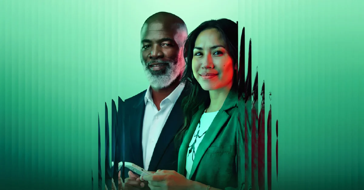 A smiling man and a smiling woman light by soft green lighting.