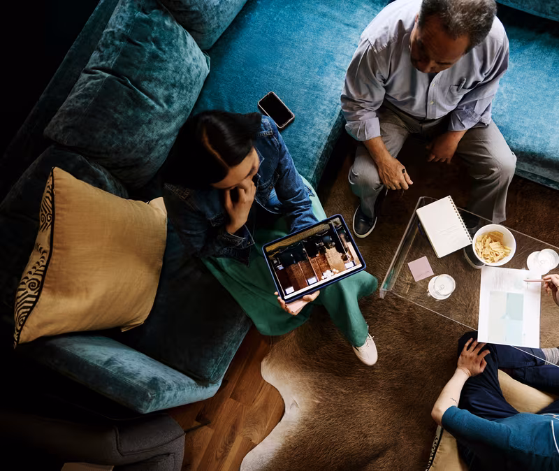 Overhead view of three people sitting around a coffee table in a living room