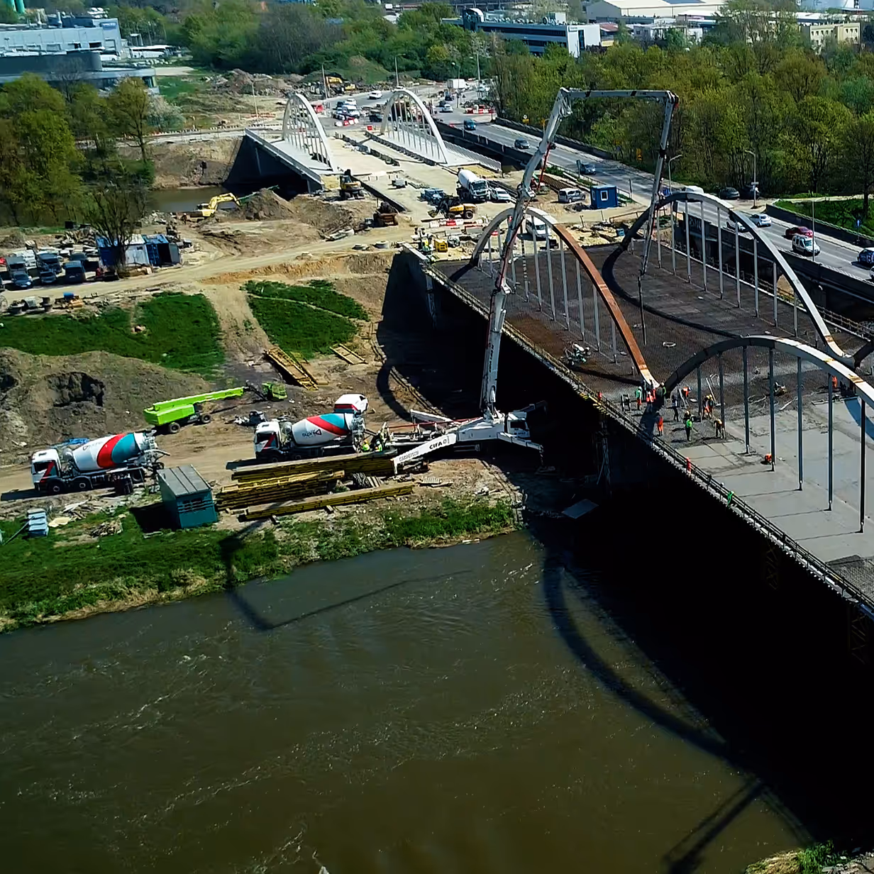 Ciężarówki z betonem na placu budowy mostu nad rzeką