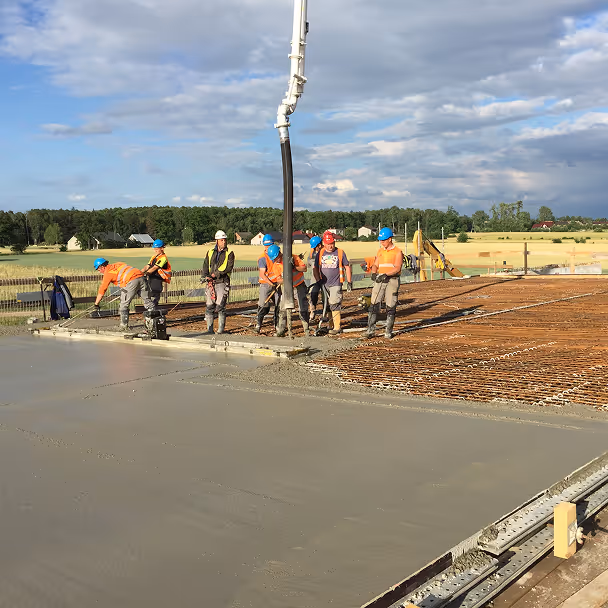 Pracownicy budowlani wylewający beton na zbrojony fundament budynku
