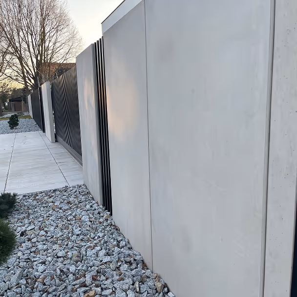 Nowoczesne betonowe ogrodzenie z elementami stalowymi, ścieżka z kostki brukowej