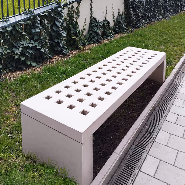 Nowoczesna betonowa ławka z otworami w zielonym otoczeniu