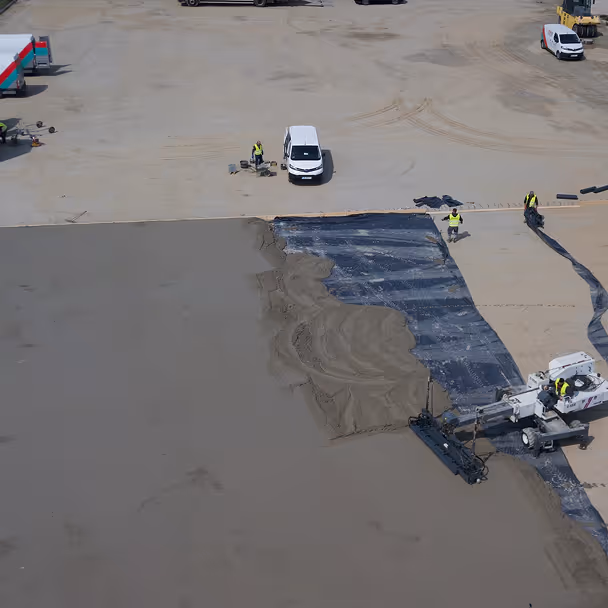 Pracownicy budowlani wyrównują świeży beton na placu budowy