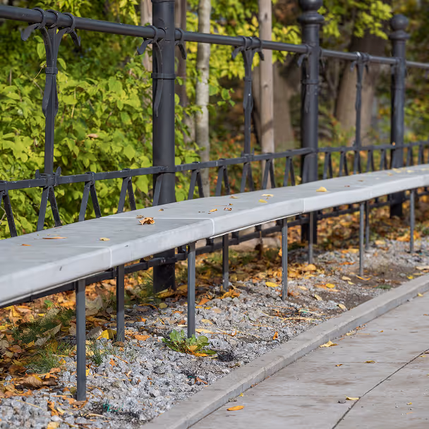 Kamienna ławka z balustradą wzdłuż chodnika w jesiennym parku