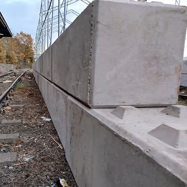 Bloki betonowe ułożone wzdłuż torów kolejowych, teren przemysłowy