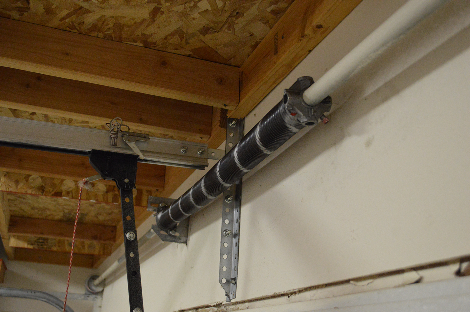 Close-up of a garage door spring system showing the torsion mechanism inside a garage