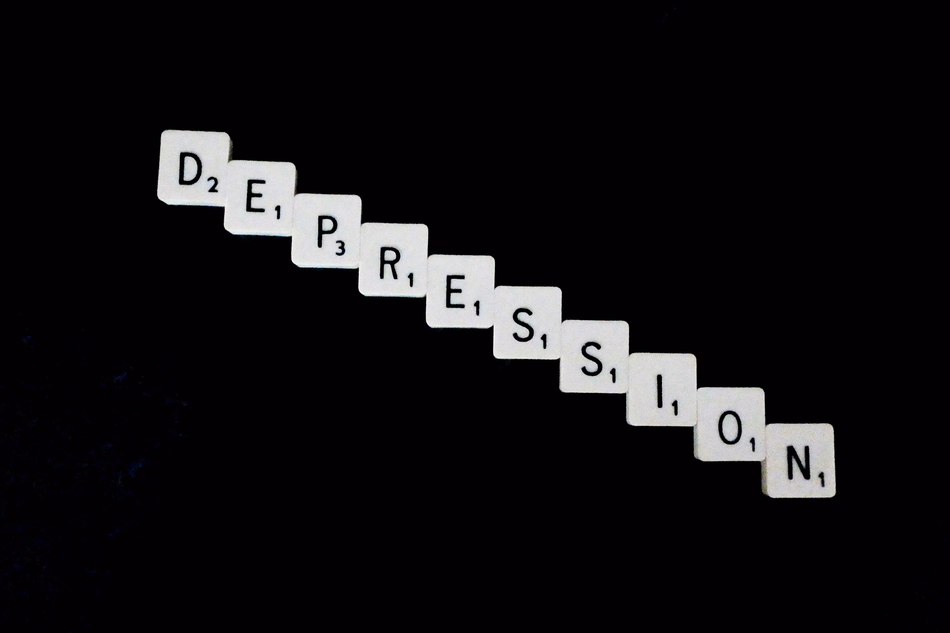 Scrabble tiles spelling out the word 'depression' on a black background