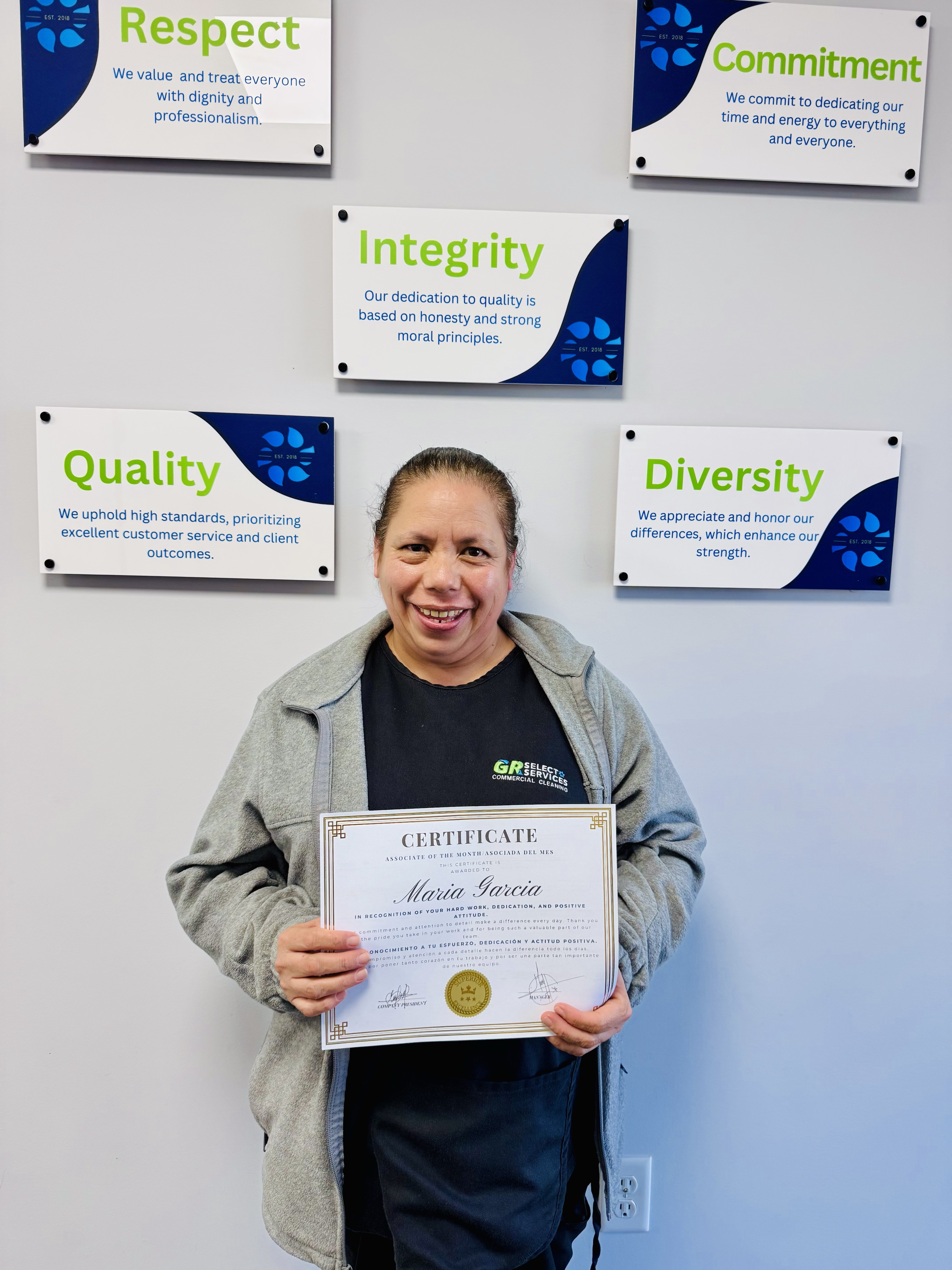 Young woman with glasses holding a certificate of appreciation for Associate of the Month awarded to Thania Luna Porcayo.