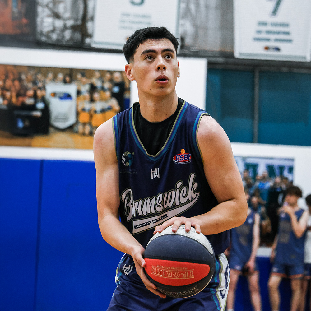 Young male basketball player in a Brunswick Secondary College jersey preparing to shoot a free throw in an indoor gym.