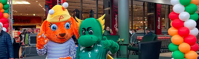 Maskottchen Luna zusammen mit grünem Maskottchen bei einem Event im Einkaufsland Wechloy