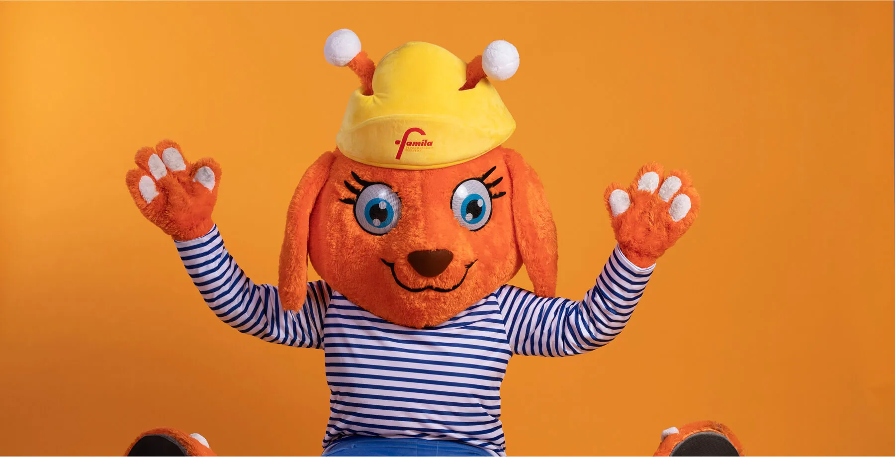 Studioaufnahme vom Famila-Maskottchen auf orangem Hintergrund
