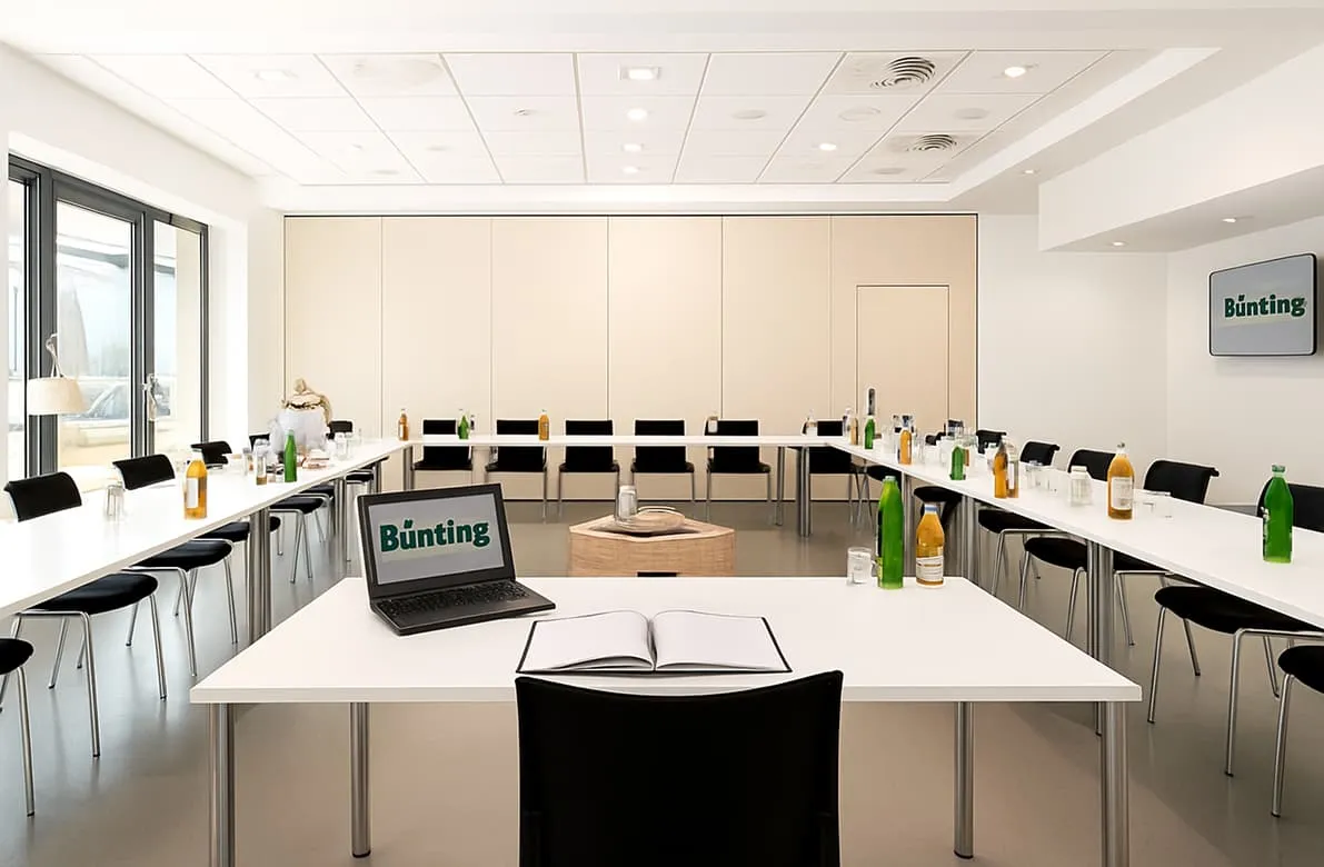 Moderner Tagungsraum „Leer“ mit U-förmiger Tischanordnung, Getränken und Tageslichtfenstern