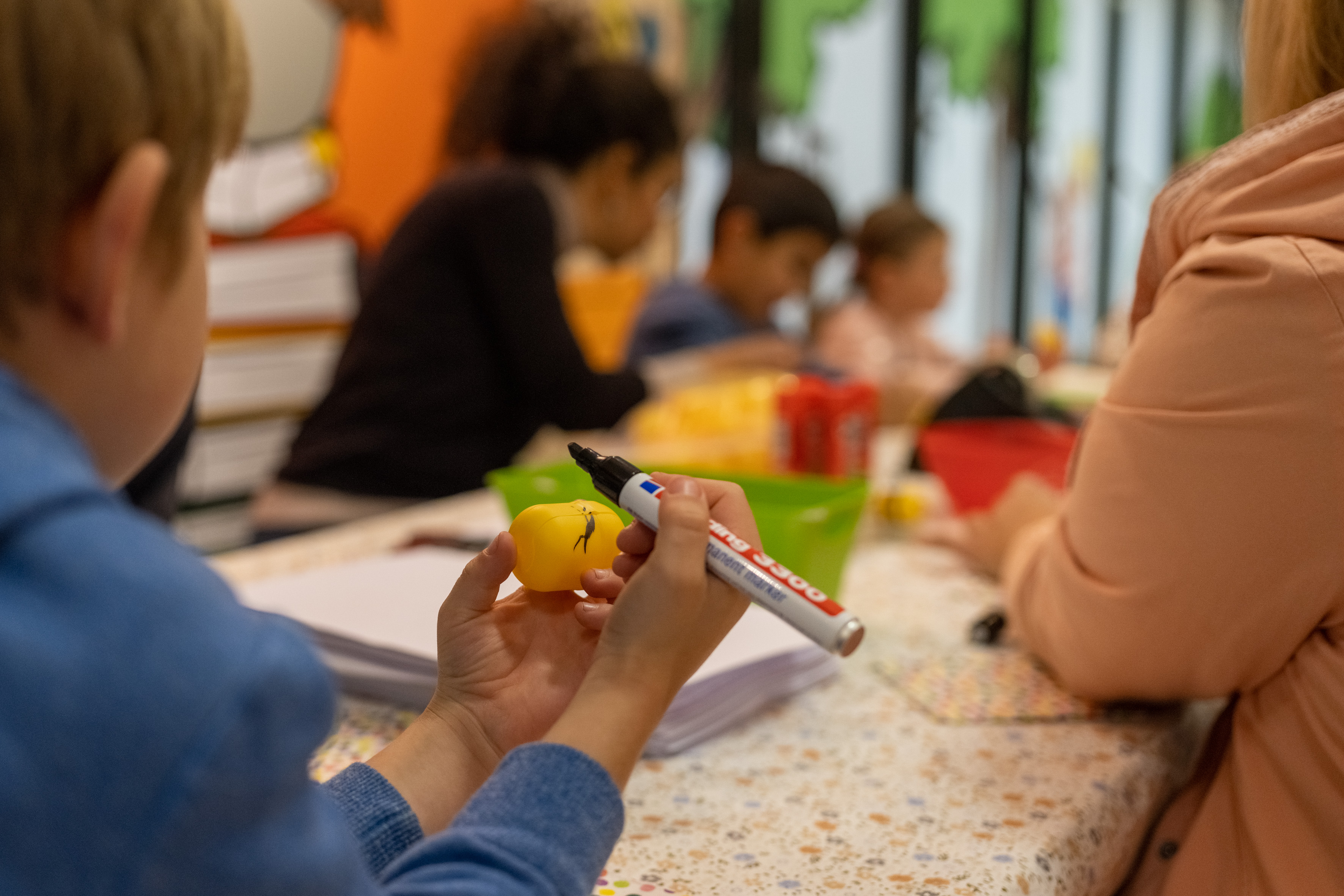 Kinder sitzen an einem Tisch und basteln Bienen aus Ü-Eiern.