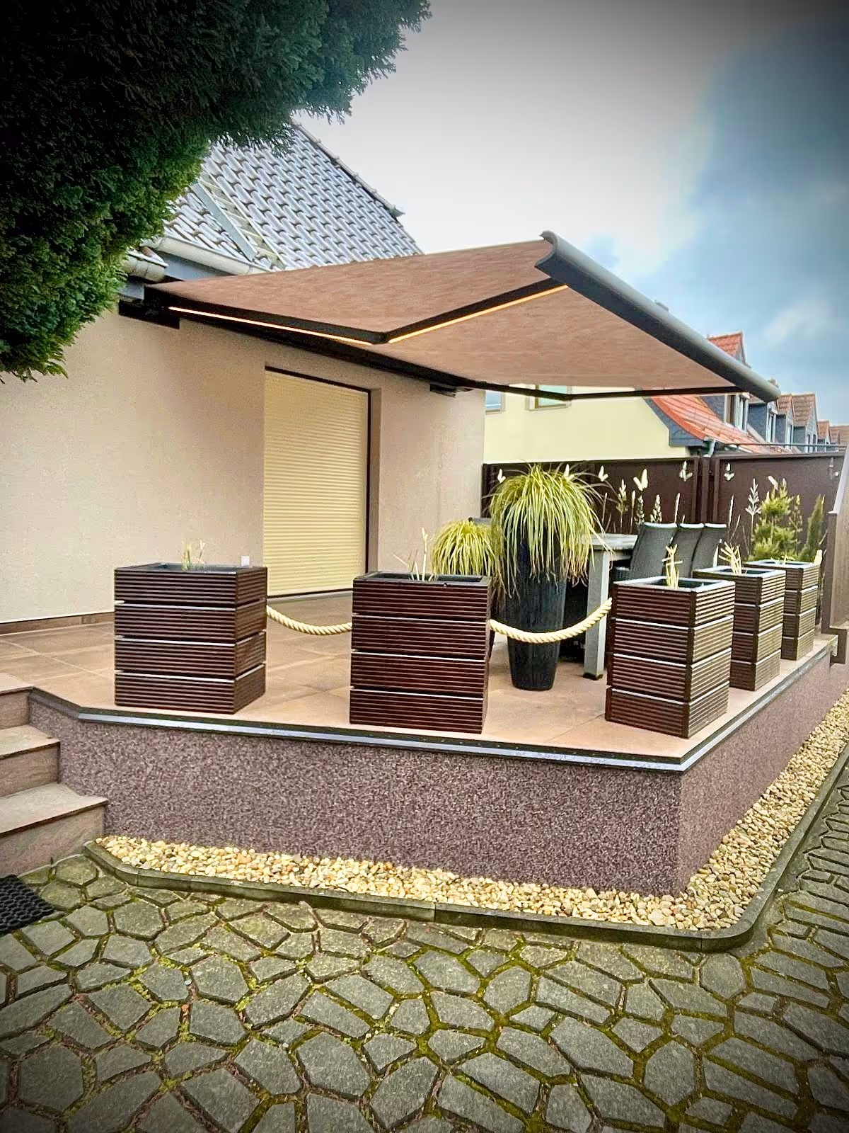 Moderne Kassettenmarkise mit integrierter LED-Beleuchtung in den Gelenkarmen für die Terrasse.
