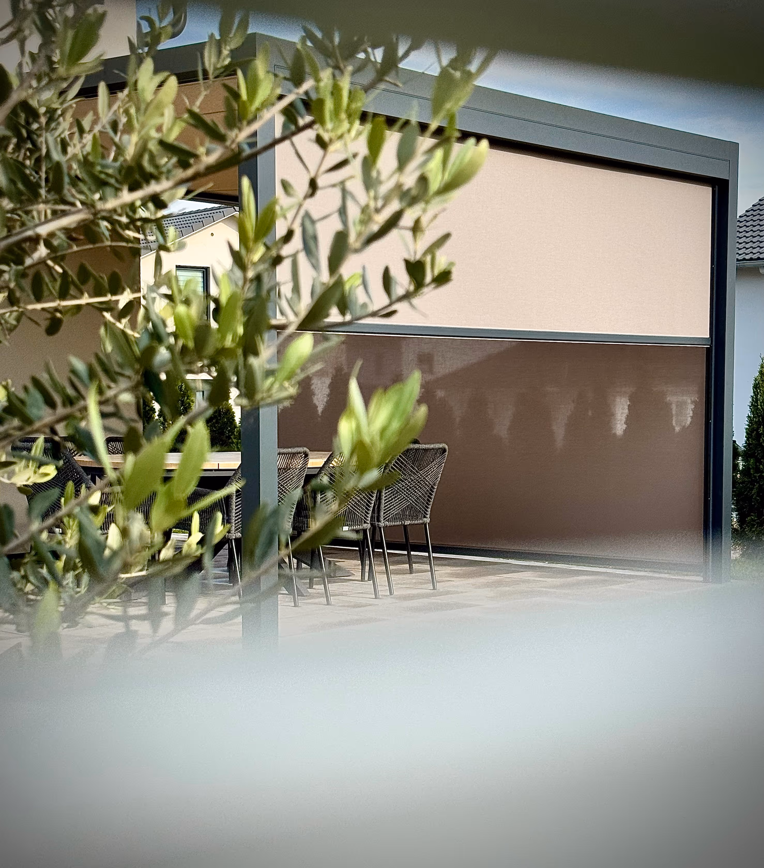 Moderne Pergola mit halb ausgefahrener Senkrechtmarkise als Sonnen- und Sichtschutz für die Terrasse.