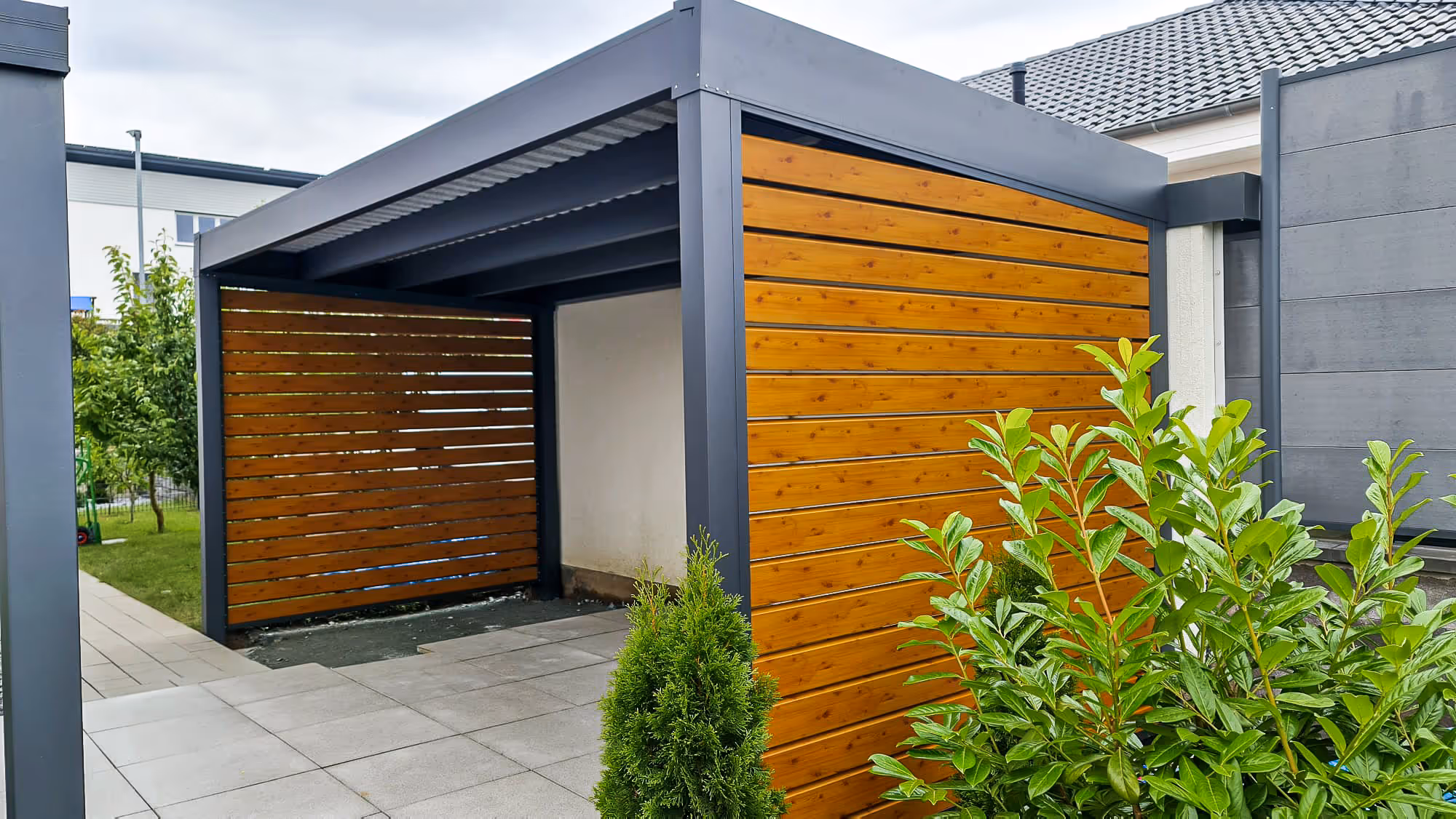 Stilvolle Einhausung im modernen Design mit Holzlamellen als blickdichter Sichtschutz.