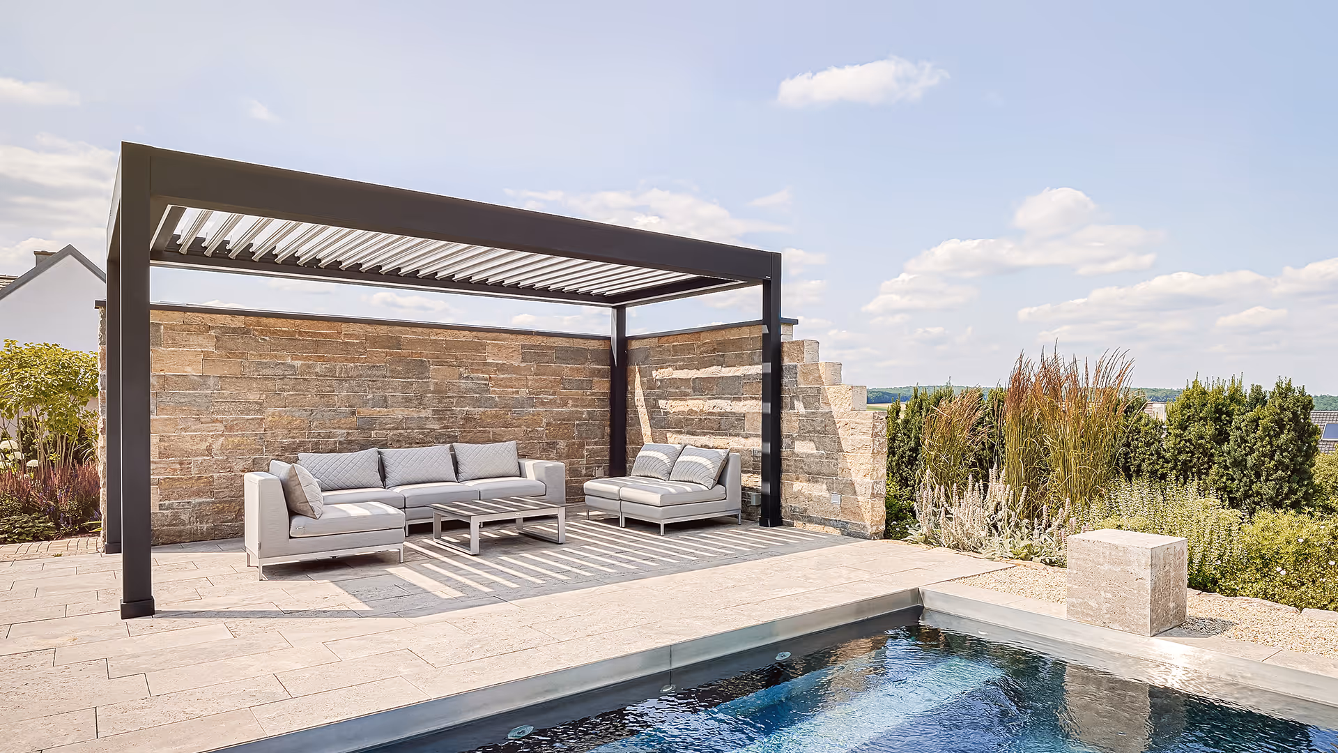 Freistehende Lamellendach-Pergola aus Aluminium als moderner Sonnenschutz für den Loungebereich am Pool.