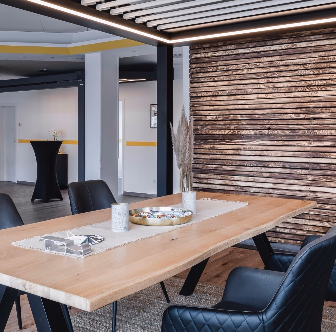 Ausgestelltes Lamellendach mit integrierter LED-Beleuchtung über einem modernen Beratungsplatz im Showroom.