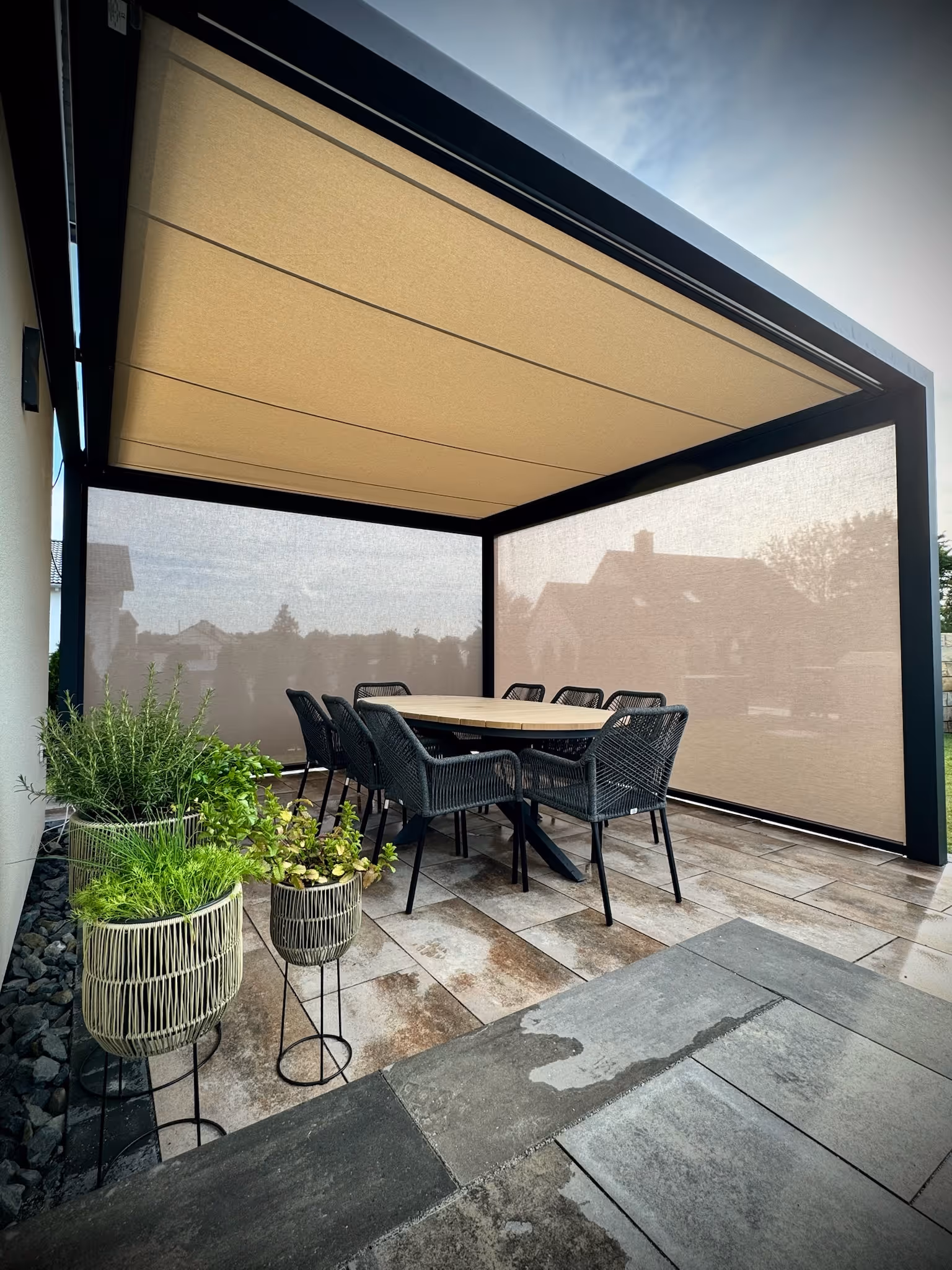 Sommerliche Terrasse, die durch rahmenlose Schiebe-Elemente und eine Markise zum Kaltwintergarten wird.