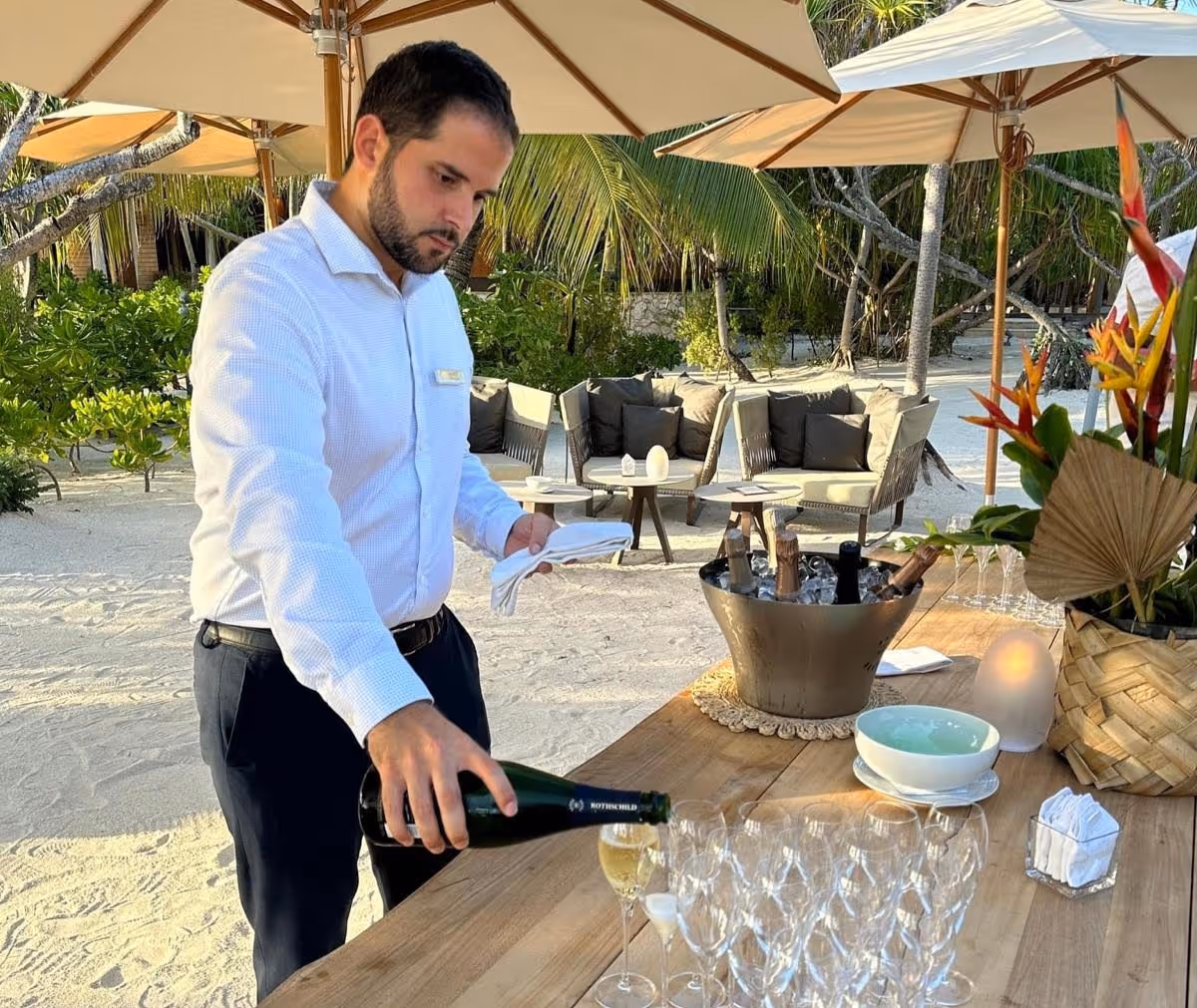 Personal Butler preparing a champagne set up on the front beach of a villa. 