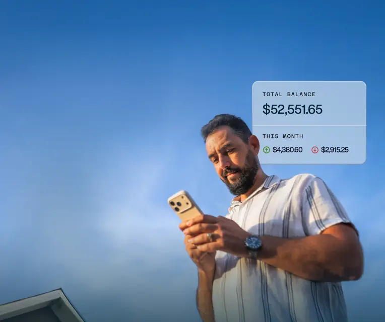 Man using smartphone outdoors with digital overlay showing a total balance of $52,551.65 and this month's income $4,380.60 and expenses $2,915.25.