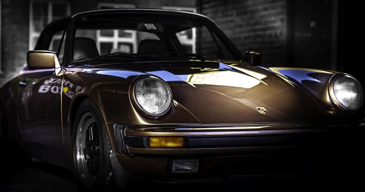 Black classic Porsche 911 parked inside an empty industrial warehouse.