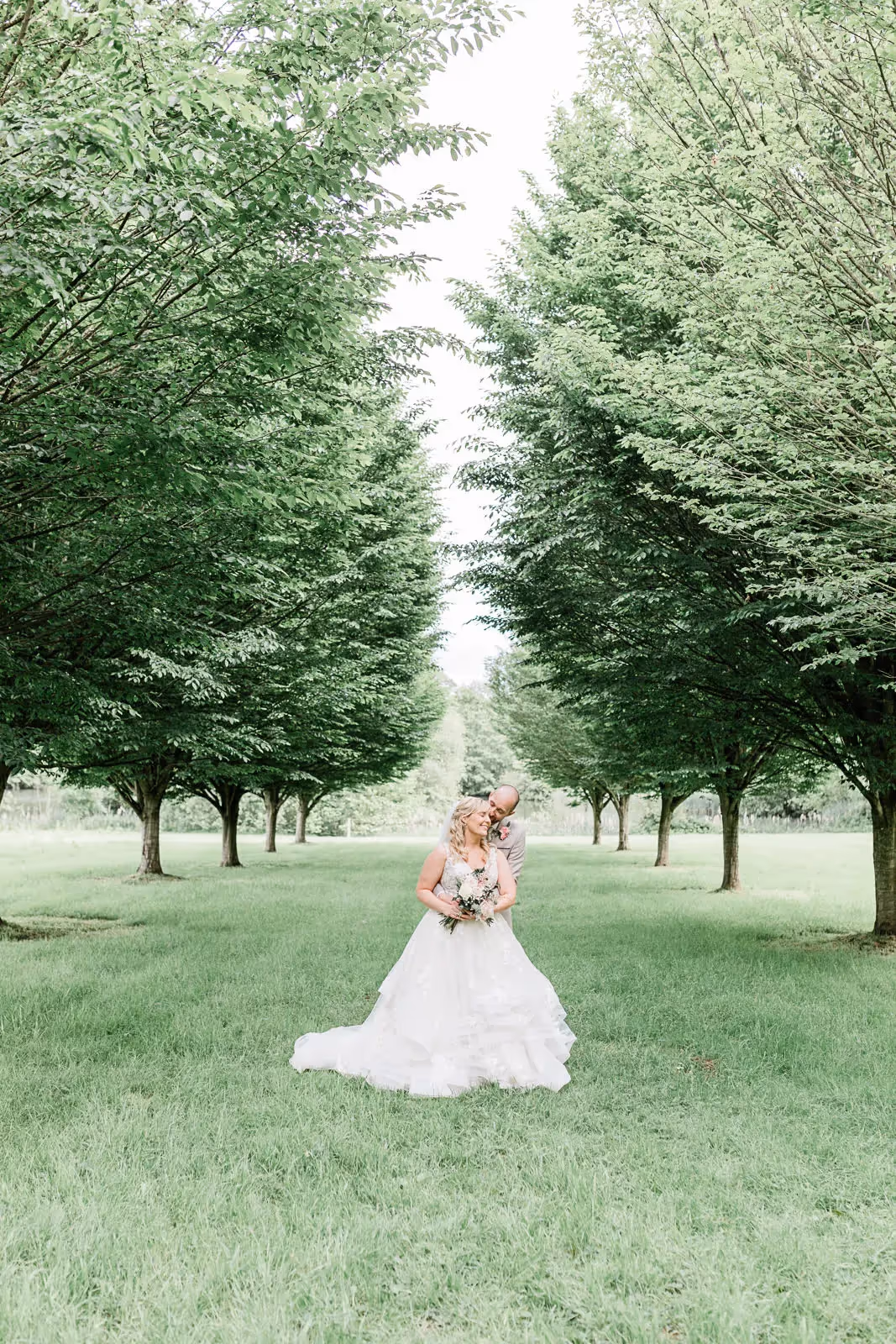 Shot of bride in estate garden amongst trees.