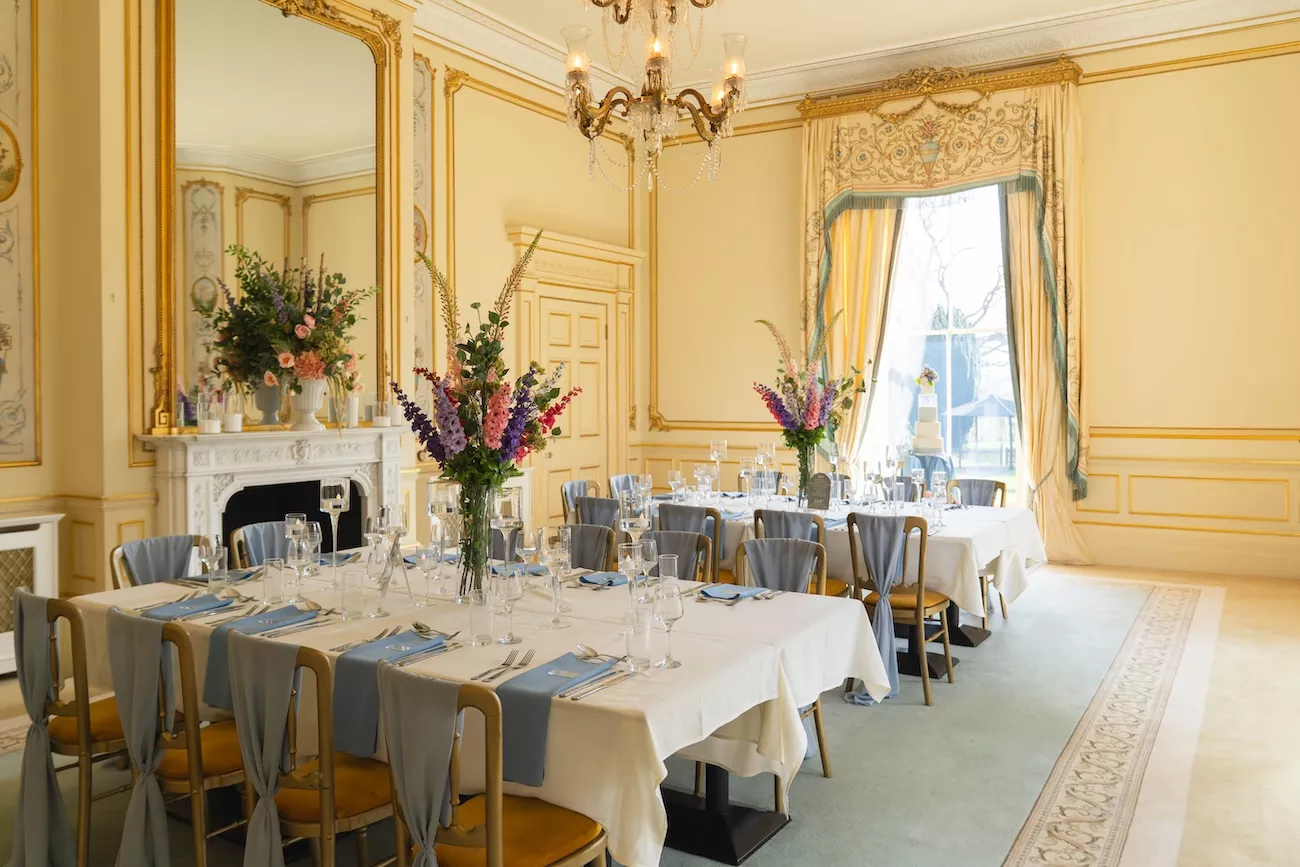 Long banqueting tables with floral displays in Netley Hall's period reception room near Whitchurch, Shropshire