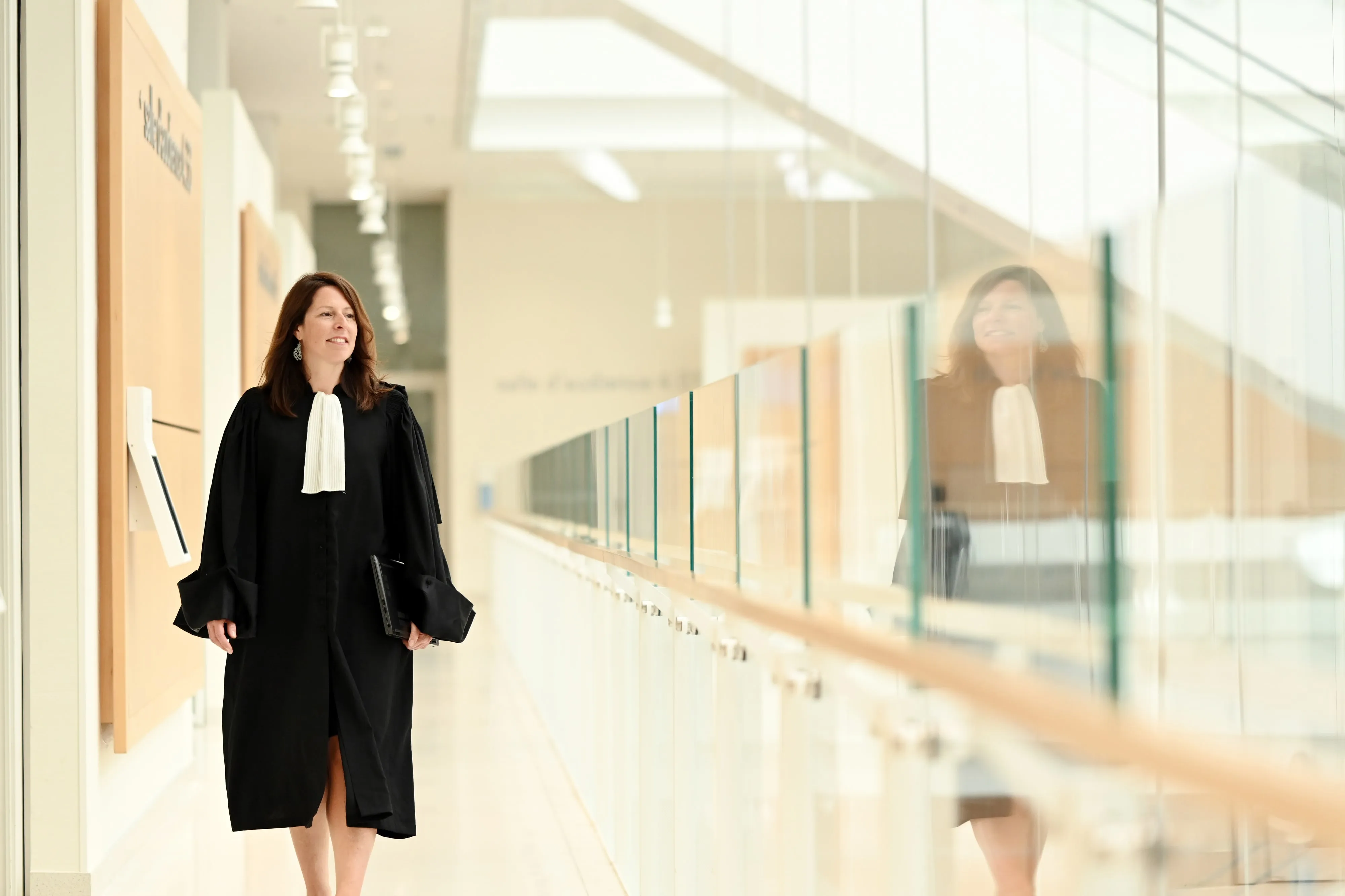 Maître Marie-Camille ECK en robe d’avocate marchant dans un couloir de tribunal, déterminée et professionnelle.